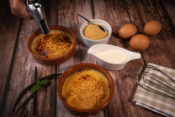 Chef cooks creme brulee with gas burner, dessert in the home kitchen, Cooking at home, professionals for food blog. High quality photo
