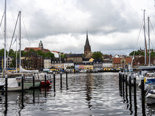 Fototapeta premium Sail boats in the port of Flensburg, St. Jorgen's Church in the background. Schleswig-Holstein in Germany