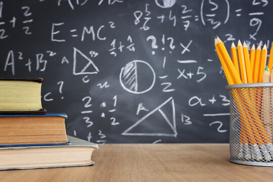 Pencils and books infront of blackboard with formulas. education concept