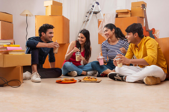 Adult boys and girls eating pizza and drinking shake during leisure time