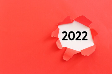 The word 2022 written under red torn paper