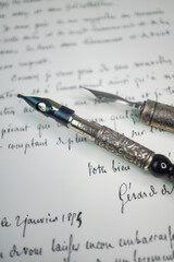 close-up vertical image Pair of antique penholders with calligraphy nibs over a manuscript 