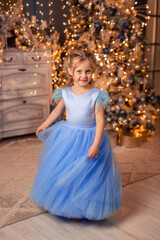 beautiful girl in an elegant dress against the background of Christmas lights and a Christmas tree in a beautiful interior