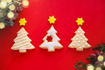 Christmas tree shaped cookies with winter decorations and bokeh lights on red background