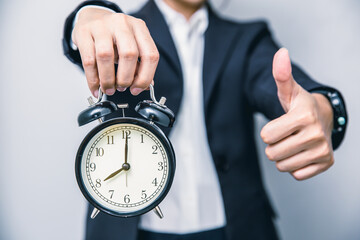 Business people thumbs up with alarm clock for punctual good time or best timing concept