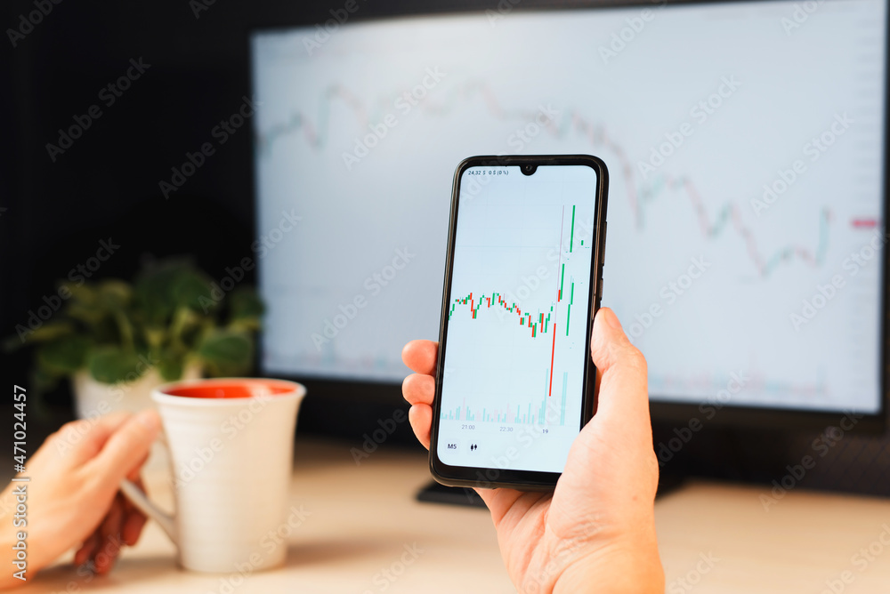 Poster trader and investor analyzing online chart of stock exchange on mobile application while sitting at 