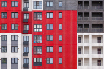 Background image - a multi-colored wall of a multi-storey building with windows and balconies