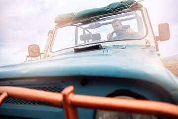 Adventure driver man on car atv cabriolet in summer, dirt and dust savannah safari tour in mountains