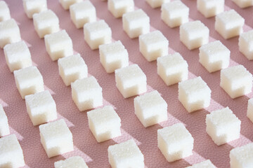 Refined sugar on pink background.Cubes of sweet and white sugar in geometricshape. Hard shadows.