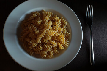 Fusilli di pasta cruda su sfondo scuro. Direttamente sopra.