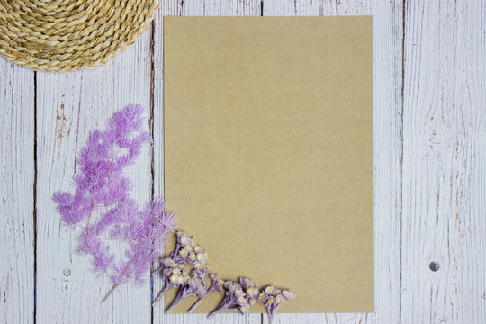 A Brown Paper With Purple Flowers On White Wooden Background. 