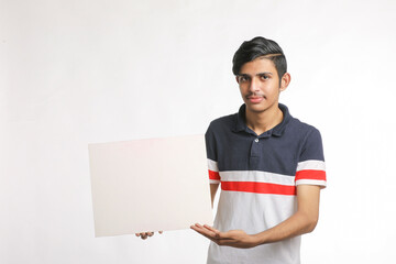 Young Indian man showing blank sing board over white background.