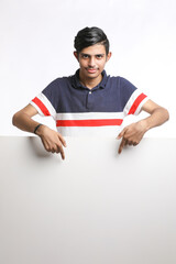 Young Indian man showing blank sing board over white background.