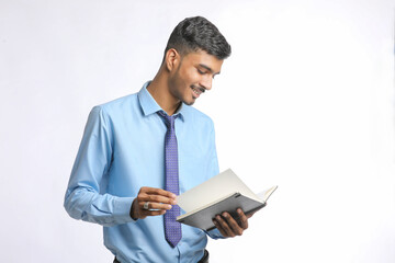 Young indian businessman cheaking or reading dairy on white background.