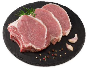 raw pork meat with rosemar, garlic and peppercorn on black round stone plate isolated on white background. Clipping path and full depth of field. Top view