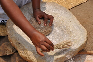 woman grinding corn on a traditional stone