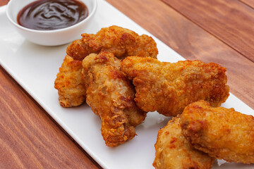 Fried chicken wings with barbeque sauce. Breaded Crispy fried chicken on wooden table. Deep fried food.