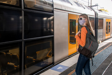 Teenage girl wearing face mask waiting for the train on the platform. Sydney trains transport NSW during Covid-19 pandemic. Mandatory face masks in public transport