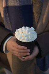 Vertical image of youthful female hands holding hot chocolate to go