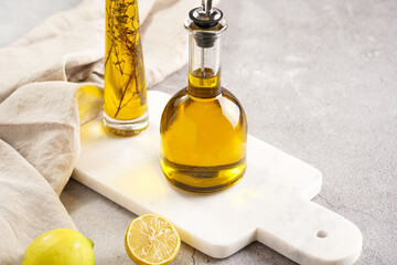 Two bottles with olive oil and fresh herbs - thyme - on white marble background
