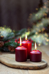 Magic Christmas. three red burning candles, christmas tree and bokeh.