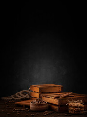 Vertical brutal stylish moody background. Wooden boxes, coffee beans, rope, cookies tied with twine, cinnamon sticks on a black background. Layout for the design. Side view.