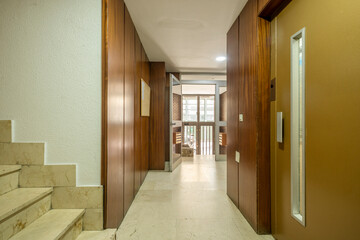 Metal elevator door in the portal of a building with floors covered in cream colored marble