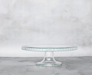 Empty glass pastry cake stand on light plain background. Horizontal frame copy space