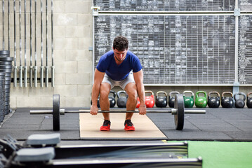 Young man beginning deadlift exercise during workout at the gym