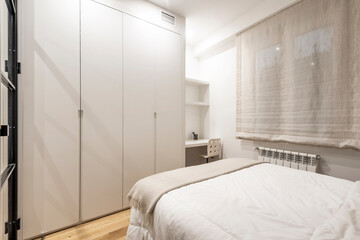 Fototapeta na wymiar Bedroom with king size bed, desk with swivel chair and large floor-to-ceiling wardrobe