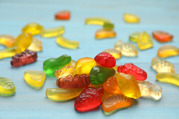 Delicious gummy fruit shaped candies on light blue wooden table, closeup