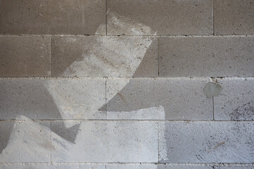 Background with a rough surface texture wall of concrete blocks with traces of paint and plaster  at a construction site