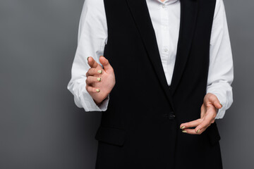 Cropped view of businesswoman pointing with finger at camera on grey background