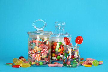 Fototapeta na wymiar Glass jars with lots of different candies on light blue background