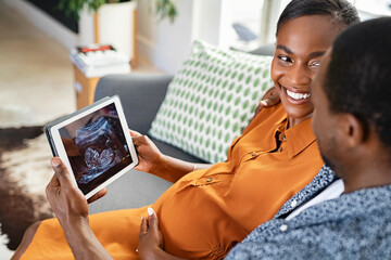 Pregnant african american couple watching ultrasound on digital tablet
