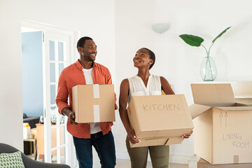 Mid adult black couple holding cardboard boxes relocating in new home