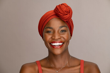 Laughing black woman with ethnic headscarf looking at camera