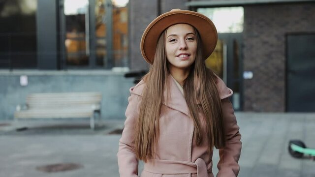 Close up pretty young woman in a coat and round hat of the city background