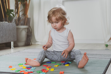 little cute toddler playing with toy letters sitting on the floor