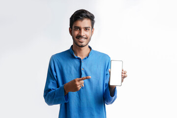 Young indian man in tradition wear and showing smartphone screen on white background.