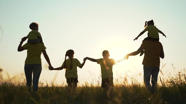 Happy family concept. Dad mom and children walk at sunset in the park. Active lifestyle concept. Parents with children holding hands at sunset. Happy family having fun in park. Silhouette of family