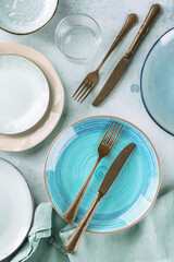 Modern dinnerware with cutlery and various plates, overhead flat lay shot on a table