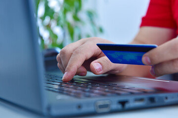 Close up of man using a credit card and purchasing products online.