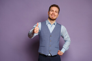 Handsome business man in a suit showing thumb up gesture isolated on a lilac background.
