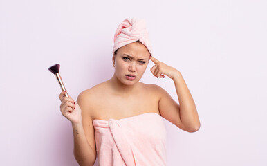 hispanic pretty woman feeling confused and puzzled, showing you are insane. make up brush concept