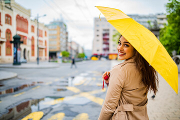 Feeling dry and protected. Attractive young woman carrying umbrella and smiling. Woman under an umbrella breathing in the street of and old town in a rainy day.