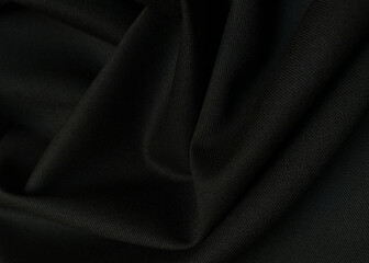 Black crumpled or wavy fabric texture background. Abstract linen cloth soft waves. Creases of satin, silk, and cotton. Smooth elegant silk or atlas luxury cloth texture. Bedding Sheets or blanket.
