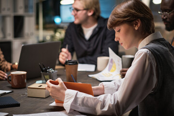Young businesswoman making notes in notebook while sitting at the table during business meeting
