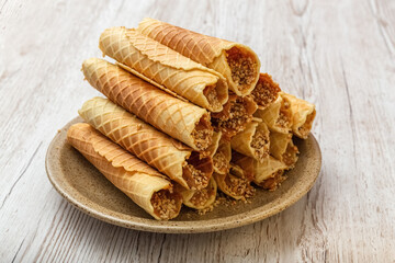 Wafer rolls with cream on a plate. Homemade baking. Wooden background. Photo