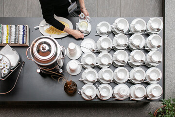 top view a woman's hands take a cup of tea from a table with hot drinks prepared by catering at the event
